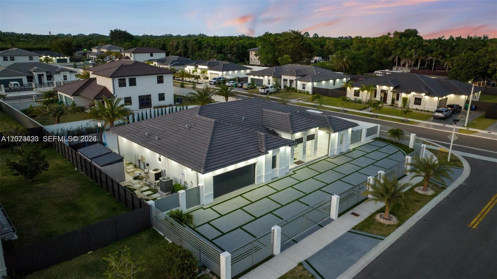 An aerial view shows a modern single-story house with a paved driveway and gated entrance — 13305 SW 190th Ter # 13305, Miami FL 33177, MIAMI, FL