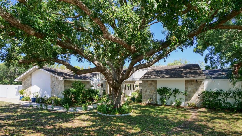 A living room features a large sectional sofa, a television, and white tile flooring — 1307 NORMANDY CIRCLE, PALM HARBOR, FL