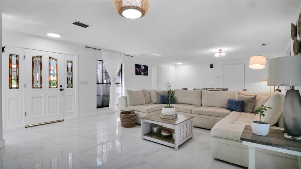 A white kitchen features a coffee station, stainless steel refrigerator, and marble-topped island — 1307 NORMANDY CIRCLE, PALM HARBOR, FL