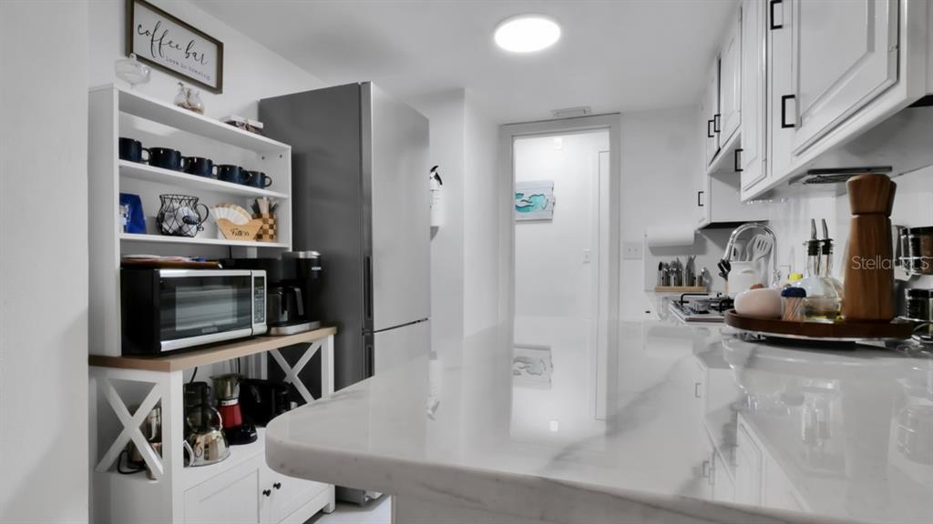 A kitchen features a large white island with wine storage, marble countertops, and tile flooring — 1307 NORMANDY CIRCLE, PALM HARBOR, FL