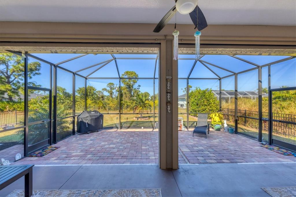 A covered patio features a brick paver floor and a screened-in enclosure overlooking a backyard — 112 BERYL DRIVE, ROTONDA WEST, FL