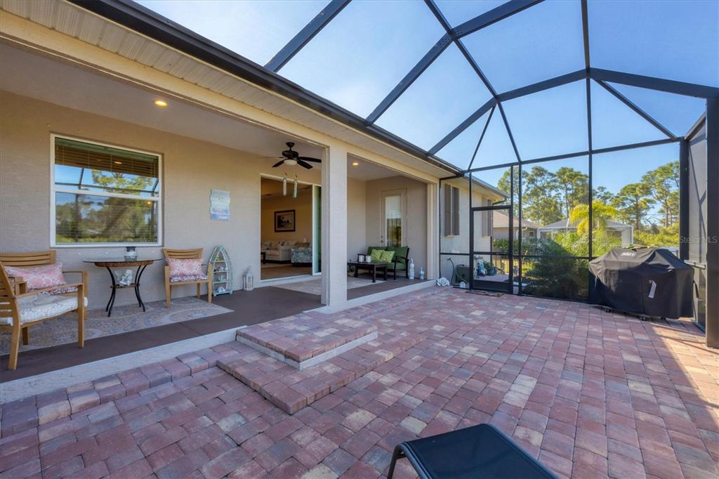A screened-in patio features a brick paver floor, a covered seating area, and a grill — 112 BERYL DRIVE, ROTONDA WEST, FL