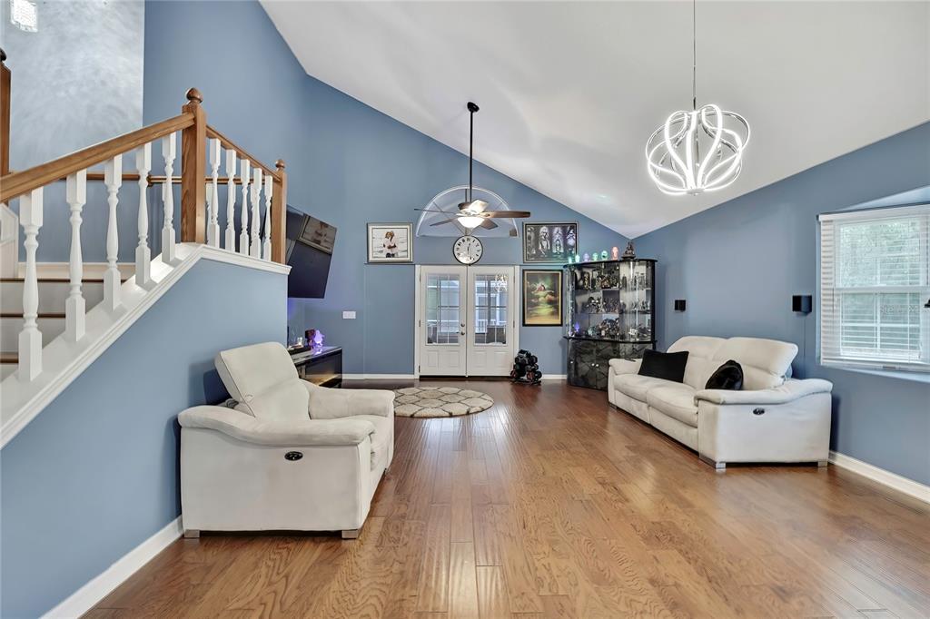 A living room features blue walls, hardwood floors, a vaulted ceiling, and white furniture — 46 GREENTREE STREET, HOMOSASSA, FL