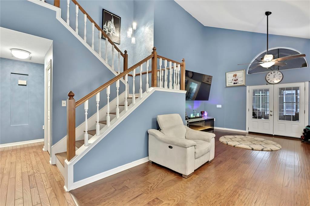 A living room features a staircase with wooden railings, light blue walls, and hardwood flooring — 46 GREENTREE STREET, HOMOSASSA, FL
