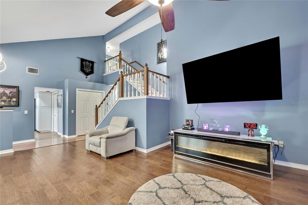 A living room features blue walls, hardwood floors, a staircase, and a wall-mounted television — 46 GREENTREE STREET, HOMOSASSA, FL