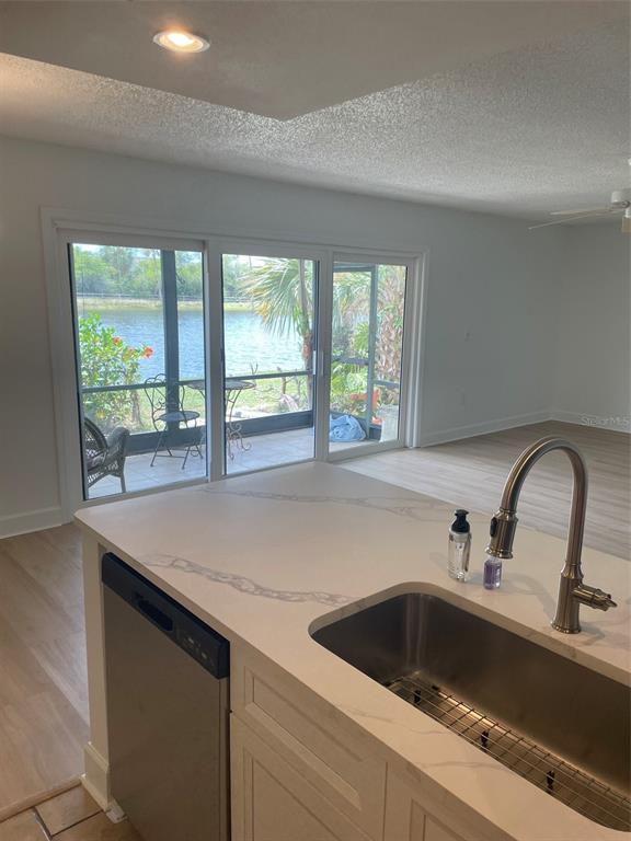 A kitchen island with a quartz countertop and sink overlooks a patio and a lake — 706 115TH UNIT 2401, ST PETERSBURG, FL