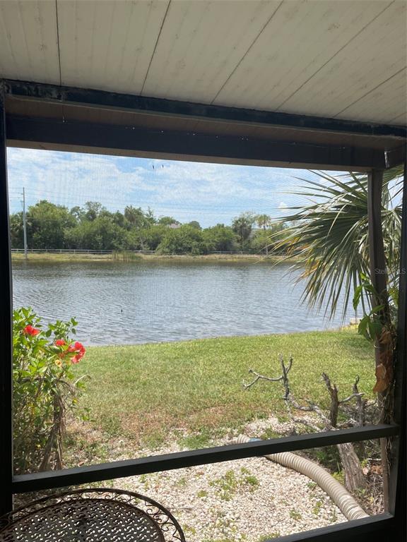 A view of a lake and grassy yard from a screened-in porch — 706 115TH UNIT 2401, ST PETERSBURG, FL