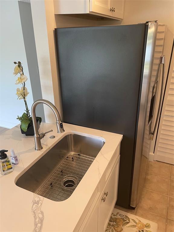 A stainless steel sink with a modern faucet sits next to a black refrigerator — 706 115TH UNIT 2401, ST PETERSBURG, FL