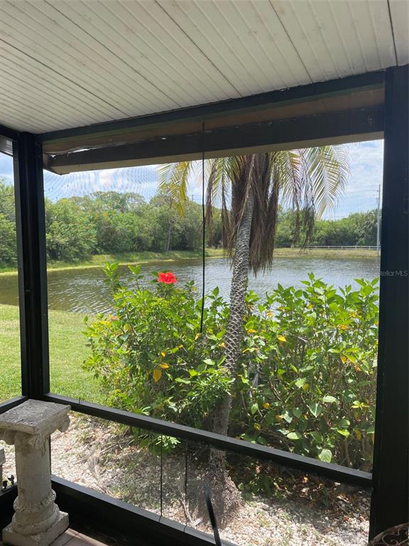 A screened-in porch overlooks a pond, a palm tree, and a hibiscus bush — 706 115TH UNIT 2401, ST PETERSBURG, FL