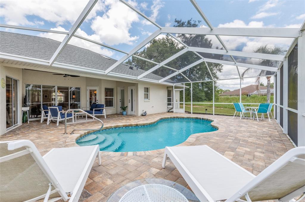 A screened-in patio features a kidney-shaped swimming pool, paver deck, and outdoor seating area — 893 N BENNINGTON TERRACE, INVERNESS, FL