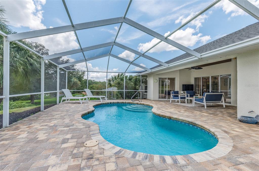 A screened-in patio features a kidney-shaped swimming pool, paver decking, and outdoor lounge furniture — 893 N BENNINGTON TERRACE, INVERNESS, FL