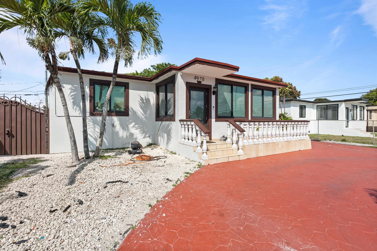 A white house with brown trim, a red driveway, and a balustrade porch — 4970 E Palm Court, Hialeah FL 33013, HIALEAH, FL