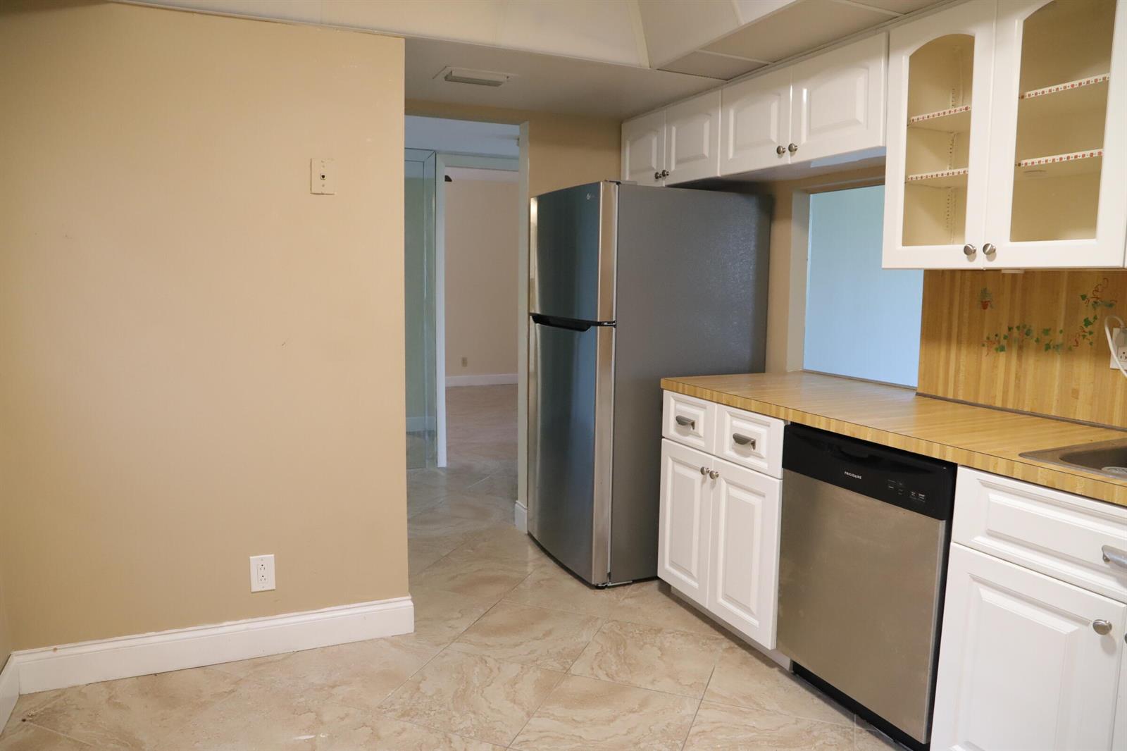 A kitchen features white cabinets, stainless steel appliances, a wood-look countertop, and beige tile flooring — 6400 NW 2nd Avenue # 423, Boca Raton FL 33487, BOCA RATON, FL