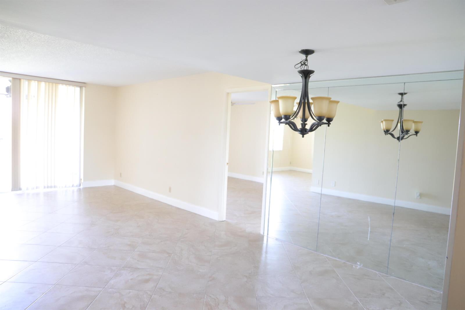 A dining area with tile floors, a chandelier, and a large mirrored wall — 6400 NW 2nd Avenue # 423, Boca Raton FL 33487, BOCA RATON, FL