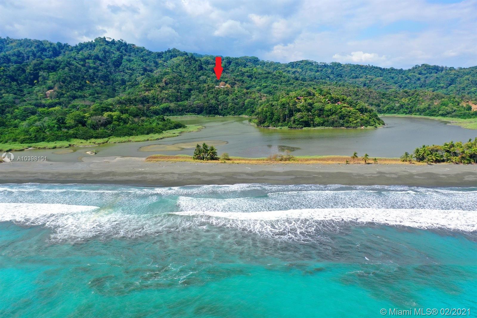 An aerial view shows a beach, a lagoon, and a house marked by a red arrow — 1 Carate Osa Peninsula, 00000, FL