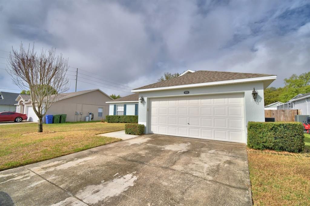 A single-story house with a white garage door, light blue siding, and a concrete driveway — 511 HEATHER GLEN DRIVE, WINTER HAVEN, FL