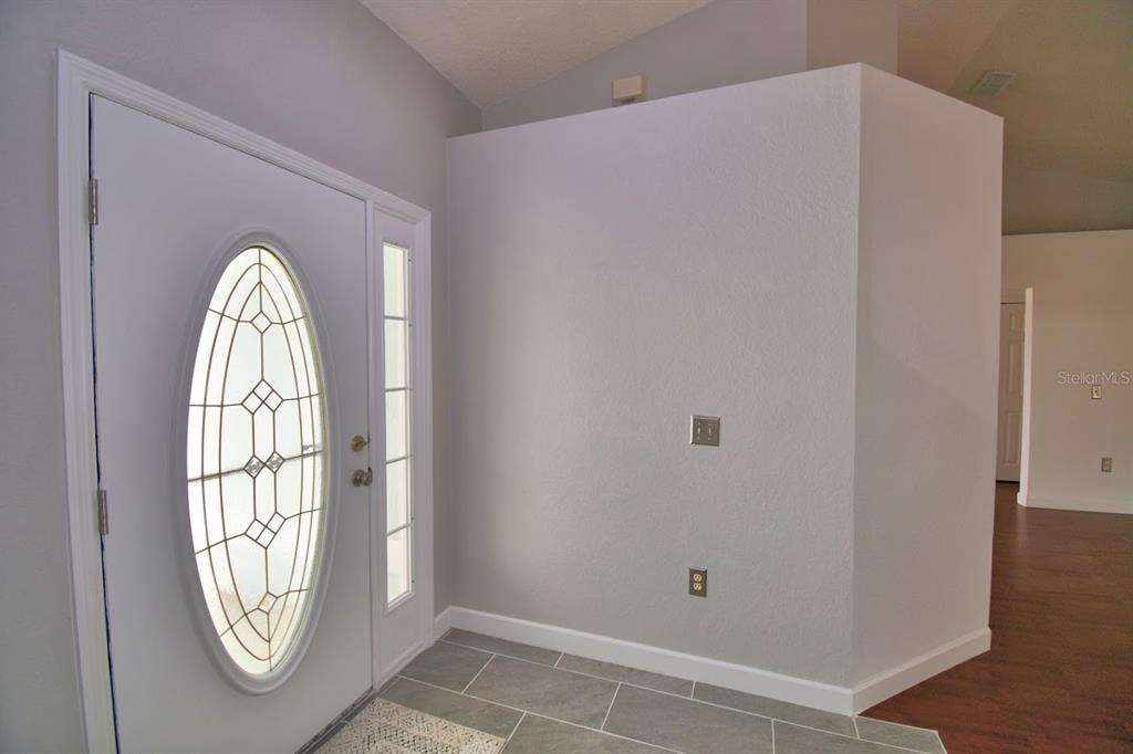 A light blue house exterior features a covered entryway with a glass-paneled front door — 511 HEATHER GLEN DRIVE, WINTER HAVEN, FL