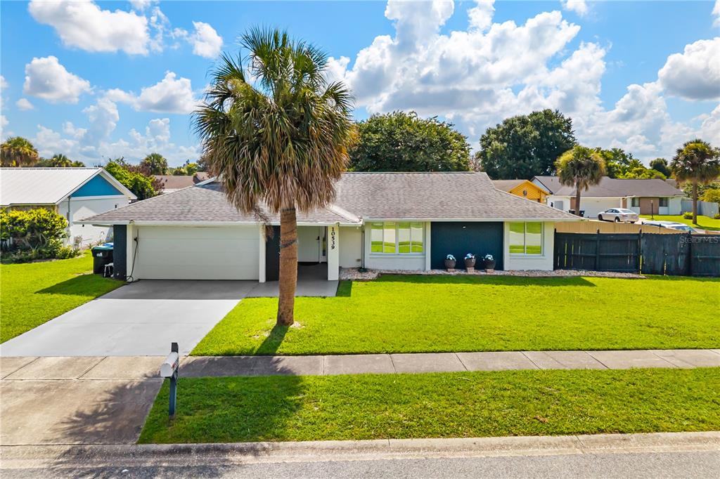 A single-story house with a white garage, a palm tree, and a green lawn — 10539 WOODWAY DRIVE, ORLANDO, FL