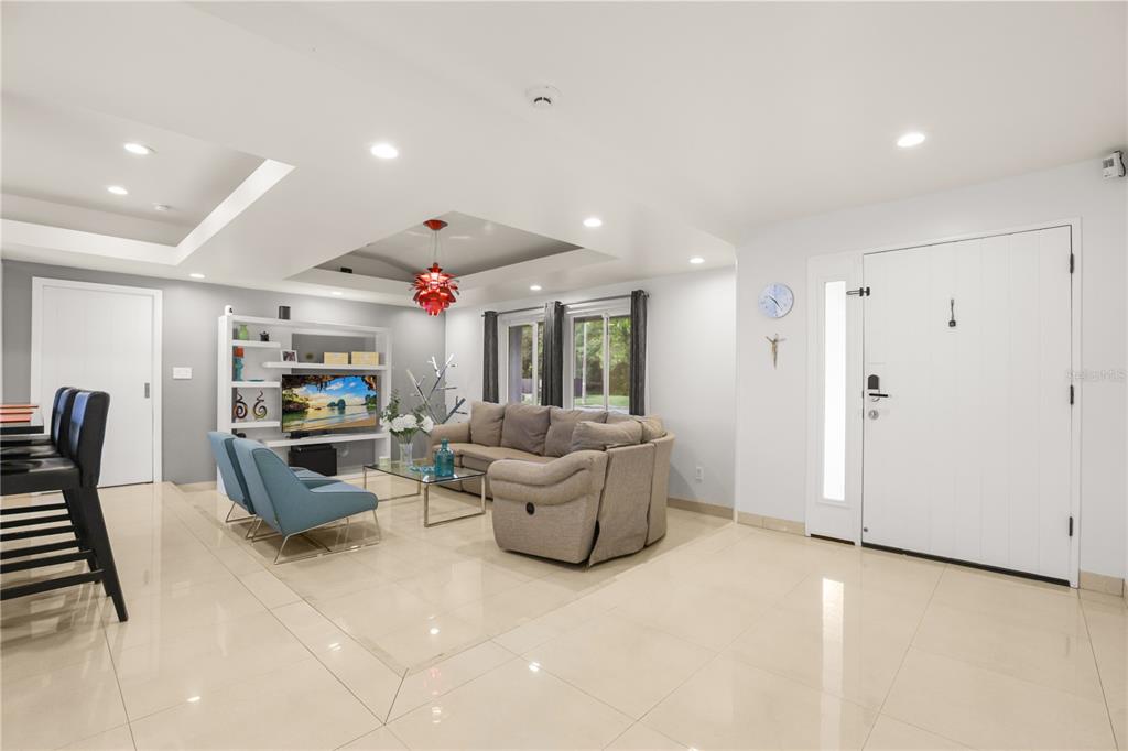 A living room features a beige sectional sofa, two blue chairs, and a red chandelier — 10539 WOODWAY DRIVE, ORLANDO, FL