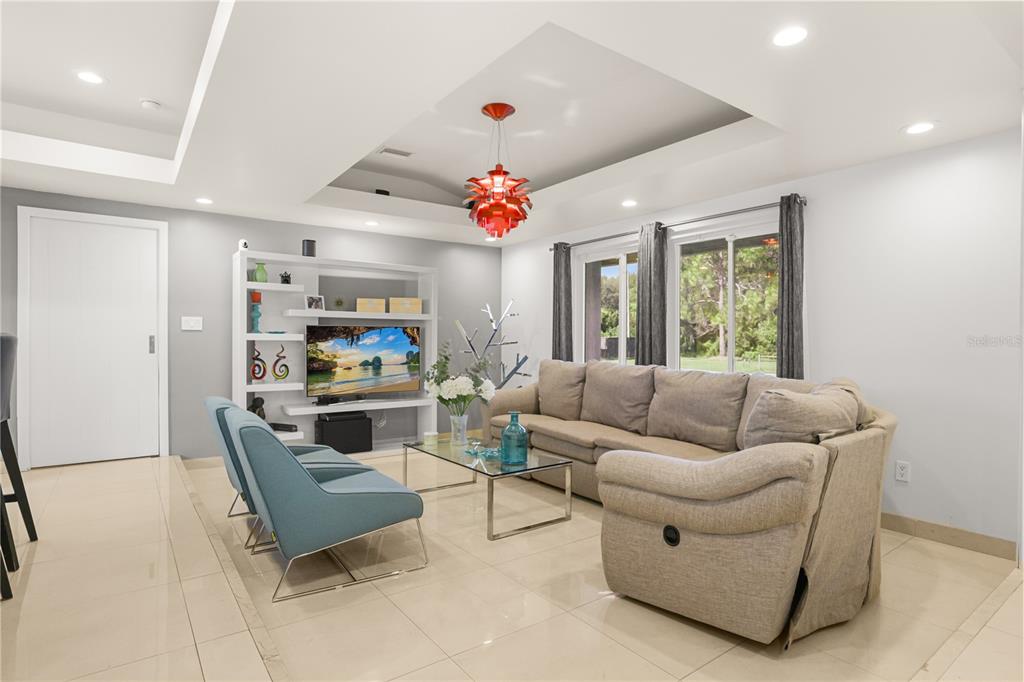 An open-concept living room and kitchen featuring a red pendant light and blue chairs — 10539 WOODWAY DRIVE, ORLANDO, FL