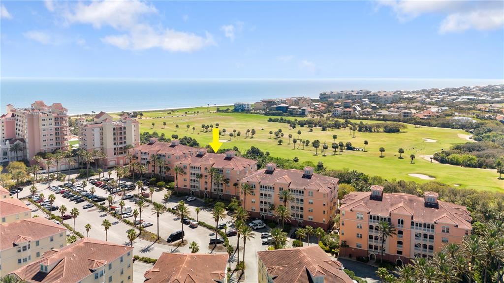 An aerial view shows multi-story peach-colored apartment buildings situated next to a golf course — 15 OCEAN CREST WAY UNIT 1324, PALM COAST, FL