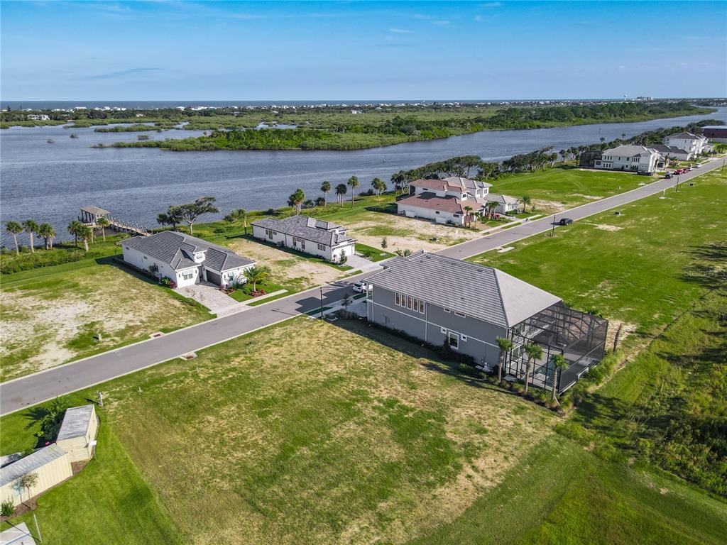 An aerial view shows several houses along a road near a body of water — 81 CORONADO ROAD, FLAGLER BEACH, FL