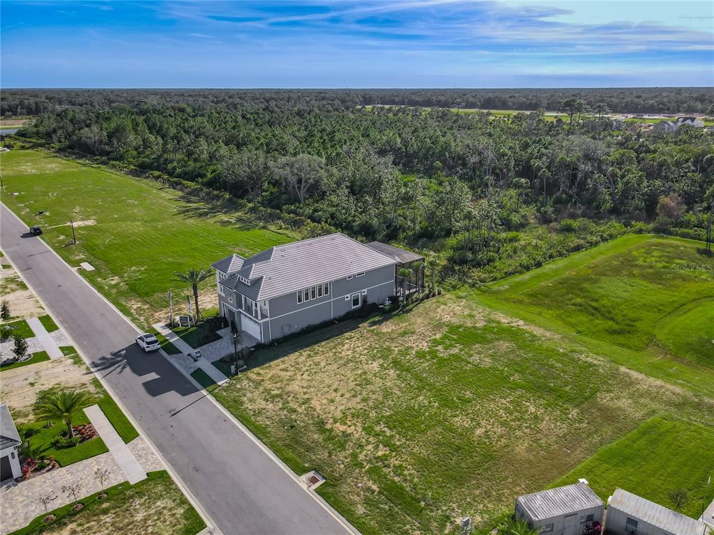 An aerial view shows a gray two-story house situated on a large, grassy corner lot — 81 CORONADO ROAD, FLAGLER BEACH, FL