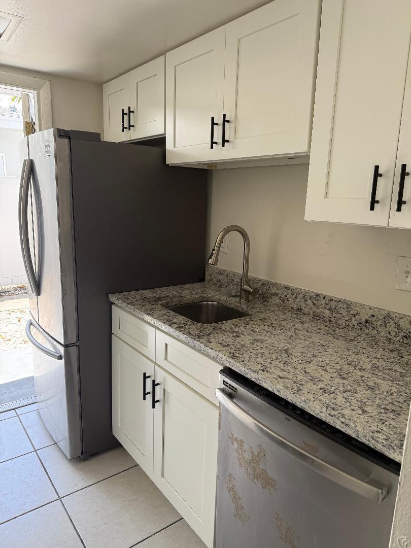 A kitchen features white cabinets, granite countertops, a stainless steel sink, and stainless steel appliances — 1913 NE 2nd Street # 1, Pompano Beach FL 33060, POMPANO BEACH, FL