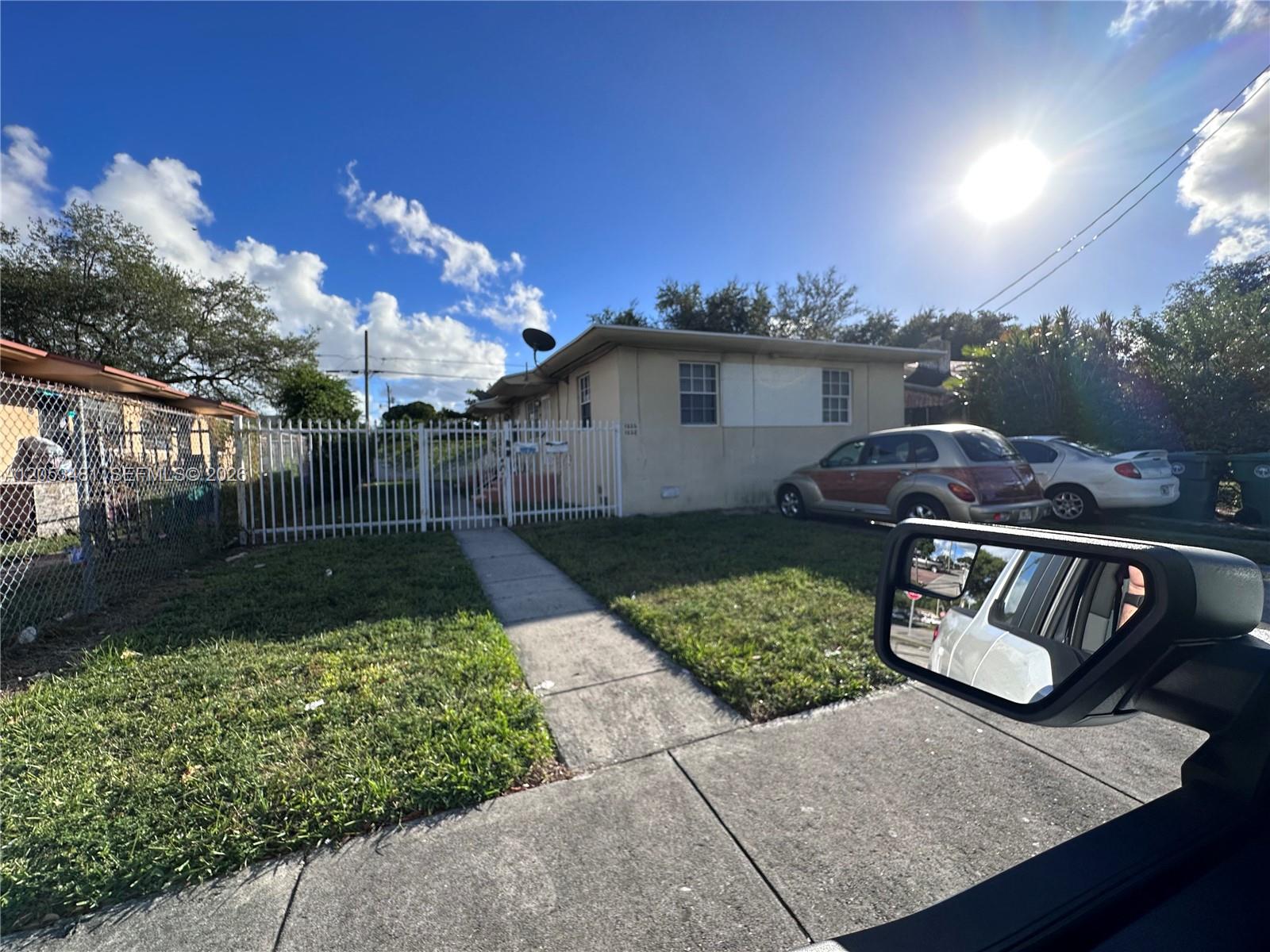 A single-story house with a white fence and two cars parked in the front yard — 1220 NW 53rd St # 1222, Miami FL 33142, MIAMI, FL