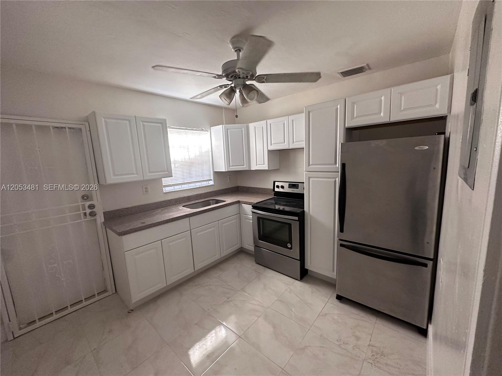 A kitchen features white cabinets, stainless steel appliances, and light-colored tile flooring — 1220 NW 53rd St # 1222, Miami FL 33142, MIAMI, FL