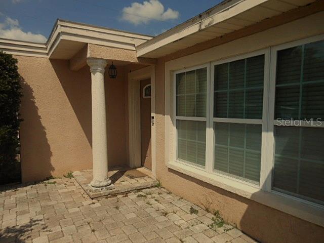 A beige house exterior features a stone-paved patio, a single white column, and large windows — 2925 W PARIS STREET, TAMPA, FL