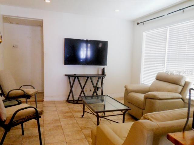 A living room features a wall-mounted television, a glass coffee table, and beige leather seating — 2925 W PARIS STREET, TAMPA, FL
