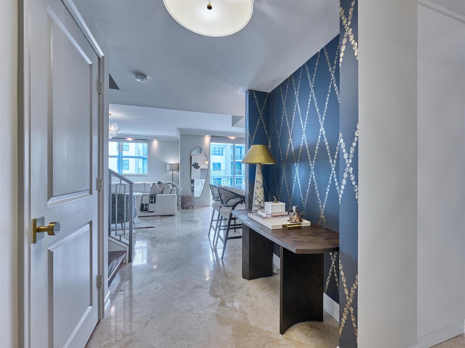 An entryway features a dark blue patterned accent wall, a console table, and marble flooring — 99 SE Mizner Boulevard # 35, Boca Raton FL 33432, BOCA RATON, FL