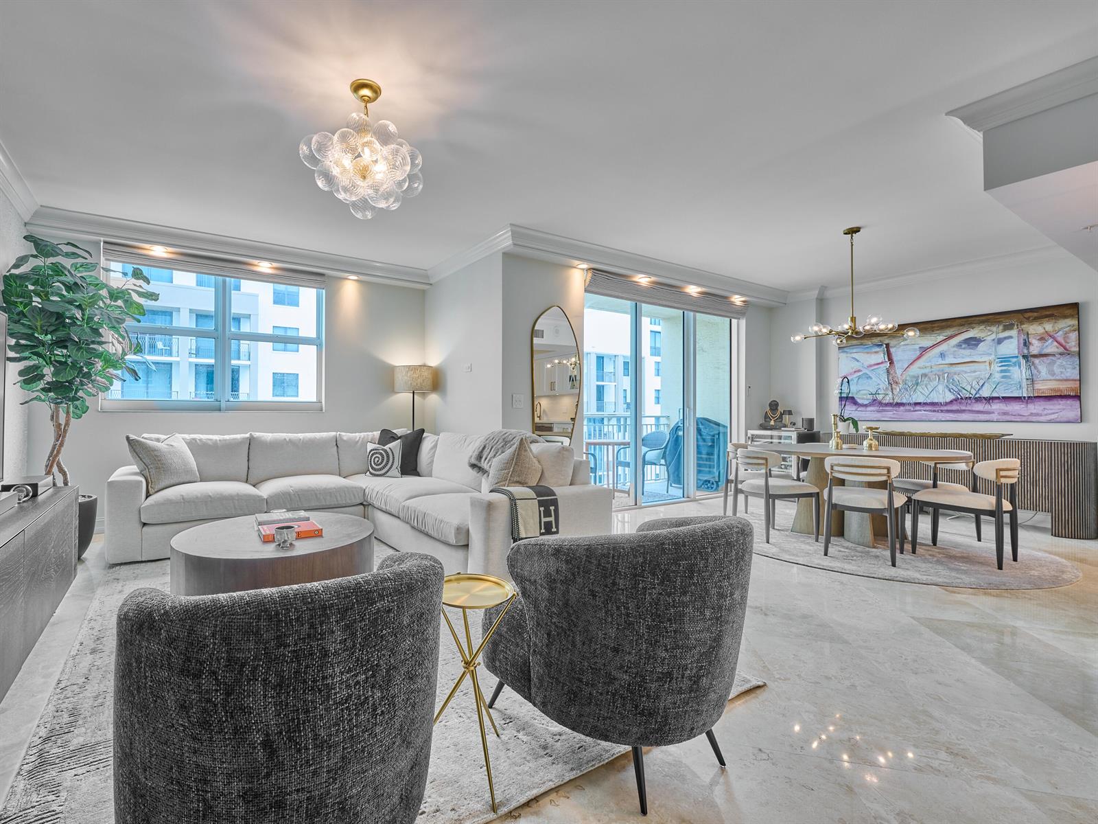 A bright, open-concept living and dining area features white furniture, gray armchairs, and marble floors — 99 SE Mizner Boulevard # 35, Boca Raton FL 33432, BOCA RATON, FL