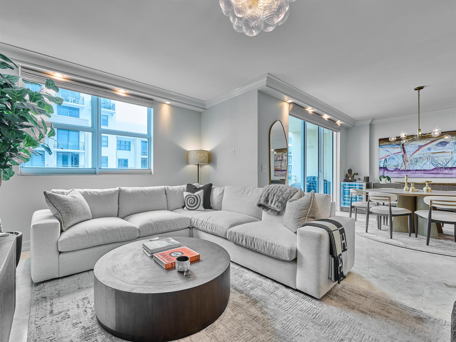 A living room features a large white sectional sofa, a round wooden coffee table, and dining area — 99 SE Mizner Boulevard # 35, Boca Raton FL 33432, BOCA RATON, FL