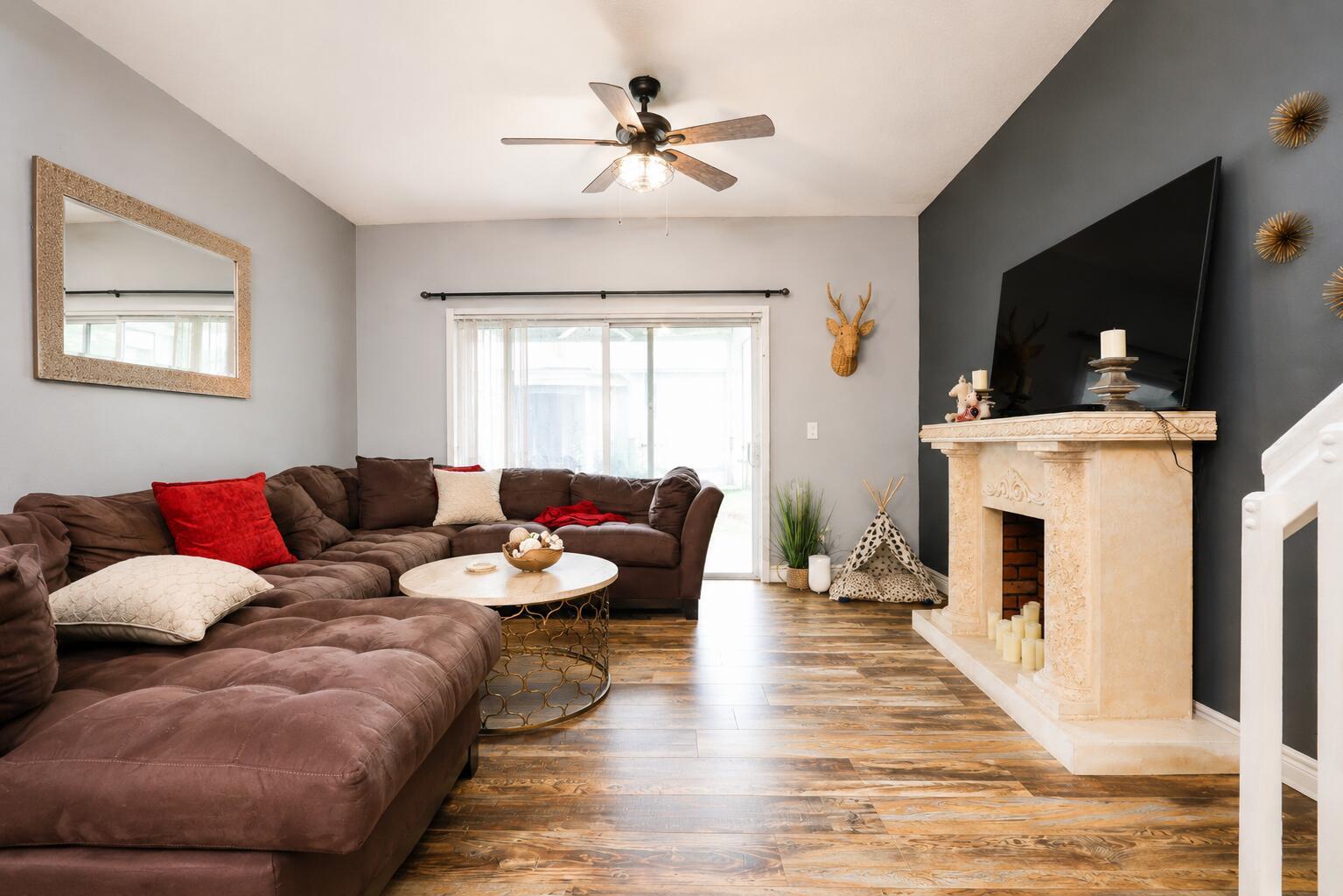 A living room features a brown sectional sofa, a fireplace with a television, and wood-look flooring — 3314 Concert Lane # 128, Margate FL 33063, MARGATE, FL