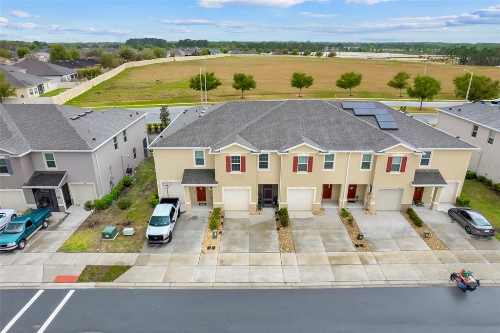 An aerial view shows a multi-unit townhouse building with driveways and a large field behind — 1041 LIDO DRIVE, HOWEY IN THE HILLS, FL