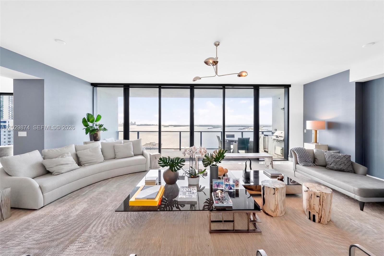 A spacious living room features a curved sofa, glass coffee table, and floor-to-ceiling windows — 1451 Brickell Ave # 2901, Miami FL 33131, MIAMI, FL