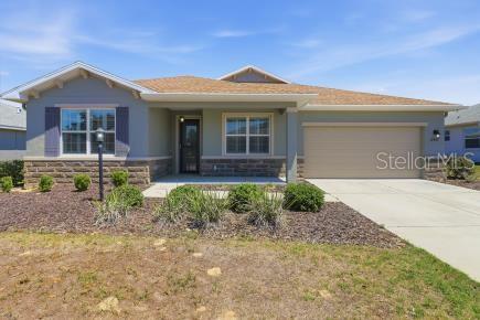 A single-story house with a tan garage, stone accents, and a covered front porch — 8907 SW 104TH CIRCLE, OCALA, FL
