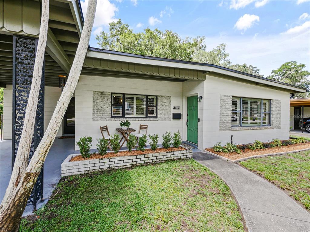 A single-story house exterior features a green front door, brick accents, and a small patio — 3112 ILLINGWORTH AVENUE, ORLANDO, FL