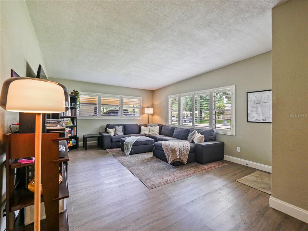 A living room features a large gray sectional sofa, wood-look flooring, and a map print — 3112 ILLINGWORTH AVENUE, ORLANDO, FL