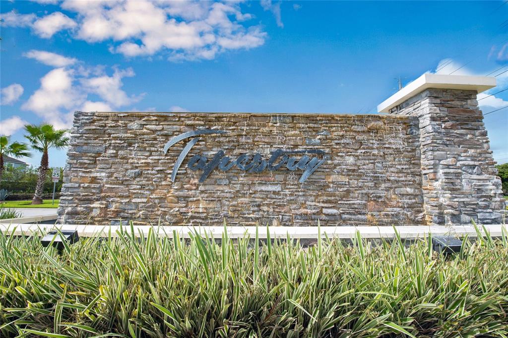 A stone wall with a water feature displays the name Tapestry in a residential community — 3018 JARDIN STREET, KISSIMMEE, FL