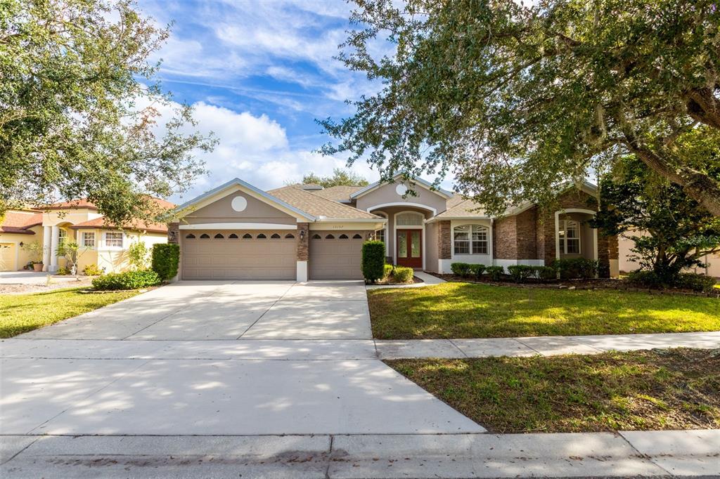 A single-story suburban house with a three-car garage, brick accents, and a large front tree — 13157 PALOMA DRIVE, ORLANDO, FL