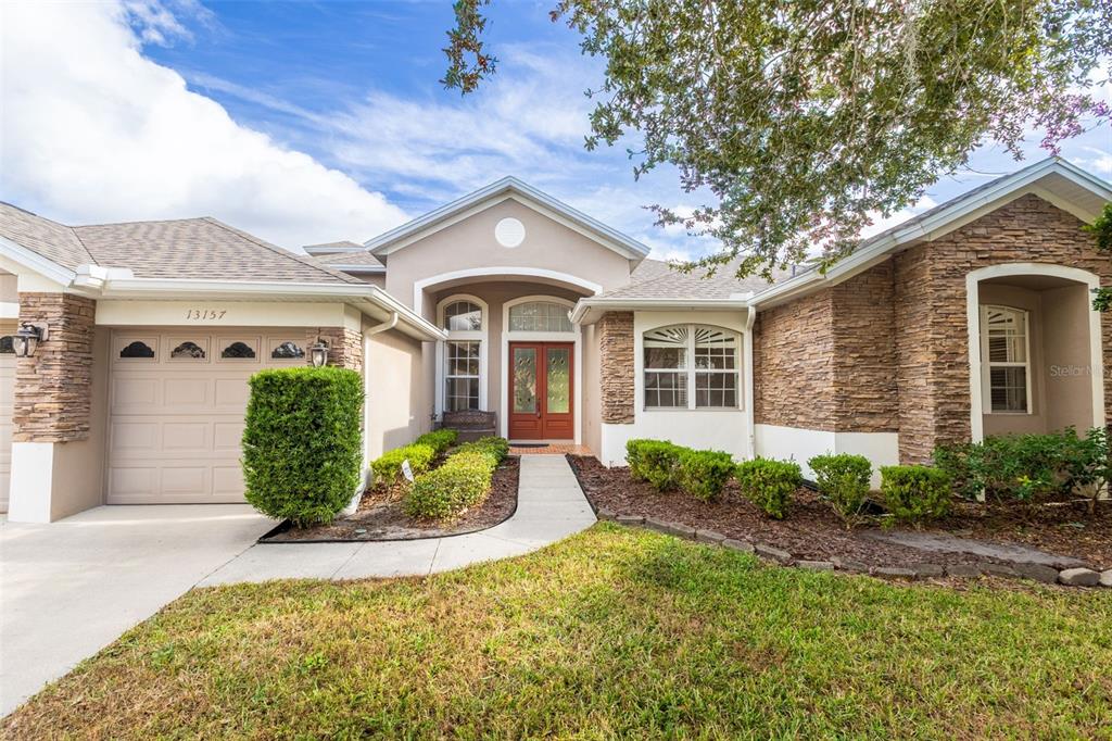A single-story house exterior features a stone facade, a tan garage, and a front walkway — 13157 PALOMA DRIVE, ORLANDO, FL