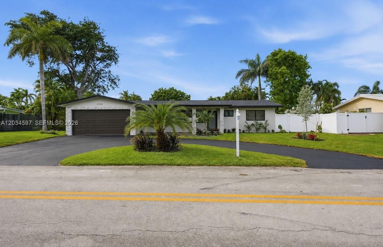 A single-story house with a dark garage door, white exterior, and a circular driveway — 2731 NE 52nd St, Lighthouse Point FL 33064, LIGHTHOUSE POINT, FL
