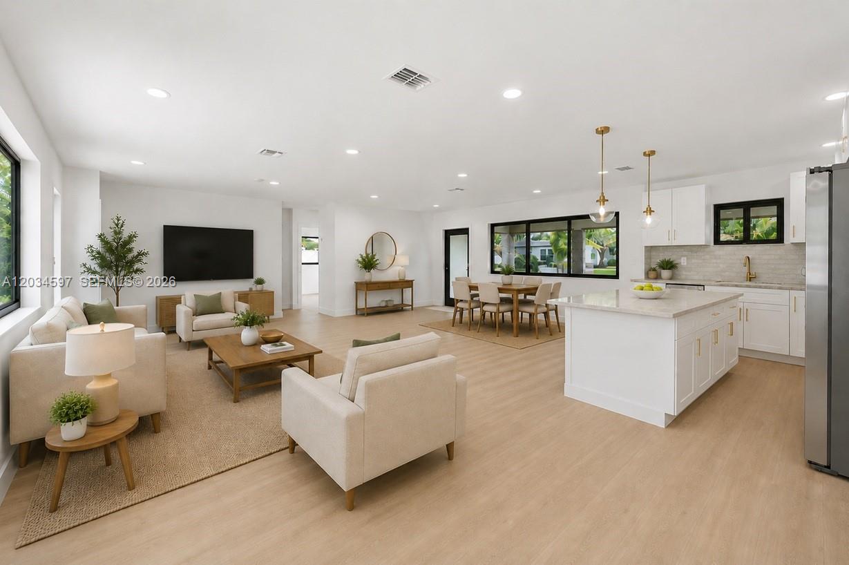 An open-concept living room and kitchen featuring white cabinetry, light wood floors, and neutral furniture — 2731 NE 52nd St, Lighthouse Point FL 33064, LIGHTHOUSE POINT, FL