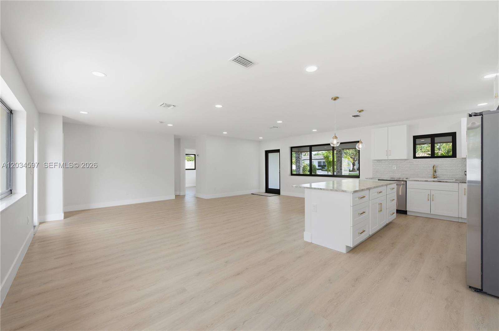 A bright, open-concept kitchen and living area features white cabinetry, light wood flooring, and recessed lighting — 2731 NE 52nd St, Lighthouse Point FL 33064, LIGHTHOUSE POINT, FL