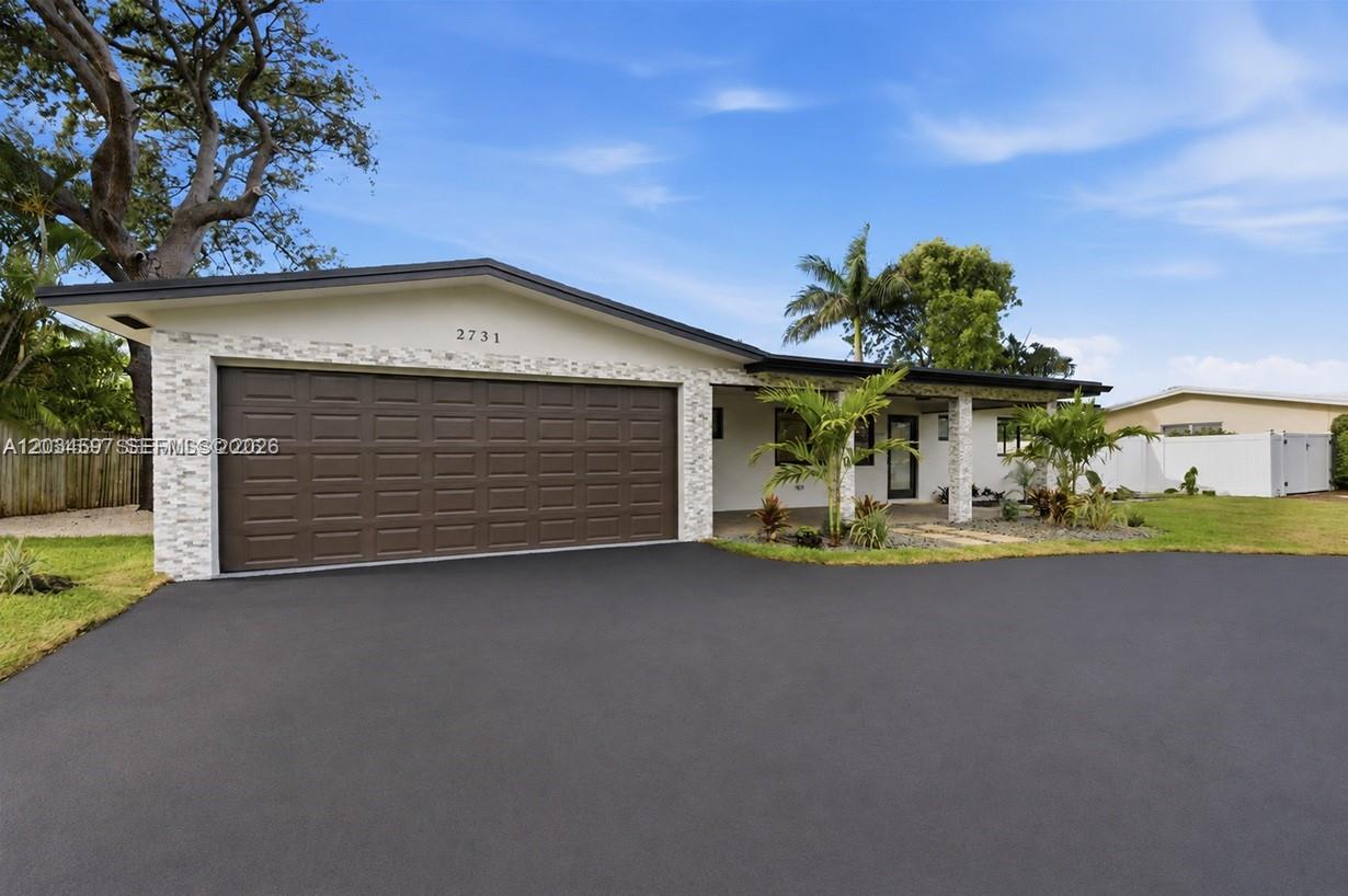 A single-story house features a two-car garage, stone veneer accents, and a paved driveway — 2731 NE 52nd St, Lighthouse Point FL 33064, LIGHTHOUSE POINT, FL