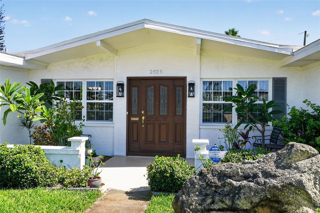 The exterior of a white house features a brown double door and large windows — 2525 CORAL WAY W, DAYTONA BEACH, FL