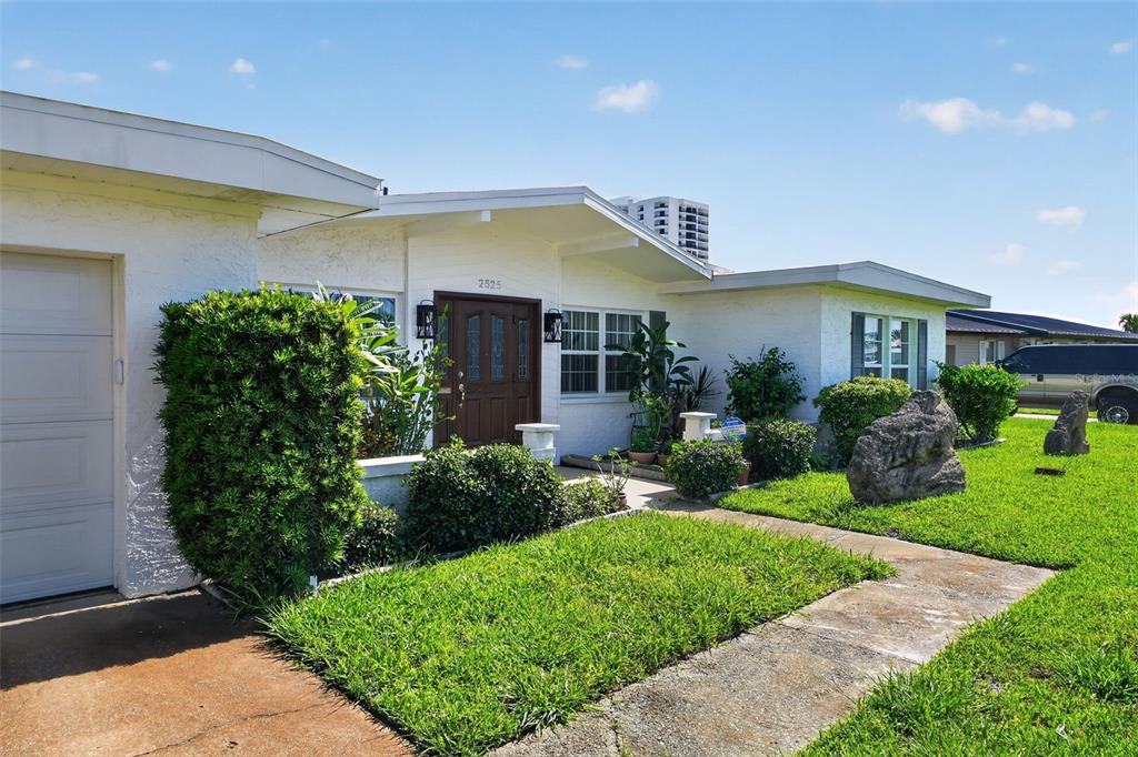 A white, single-story house with a brown front door and a green lawn — 2525 CORAL WAY W, DAYTONA BEACH, FL
